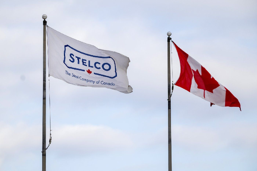 A Stelco flag flies beside a Canadian flag at the steel production facility in Hamilton, Ont., on Monday, February 10, 2025.