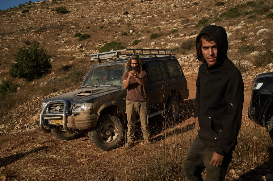 Israeli settlers block a road before Palestinians are prevented from continuing to harvest olives in the West Bank village of Deir Abu Mashal, Monday, Oct. 19, 2026.