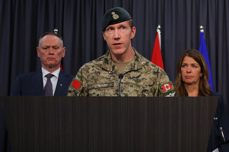 Major-General L.W. Rutland, centre, speaks as National Defence Minister David McGuinty, left, and Alberta Premier Danielle Smith, right, listen during a press conference in Edmonton, Sunday, Oct. 18, 2026.